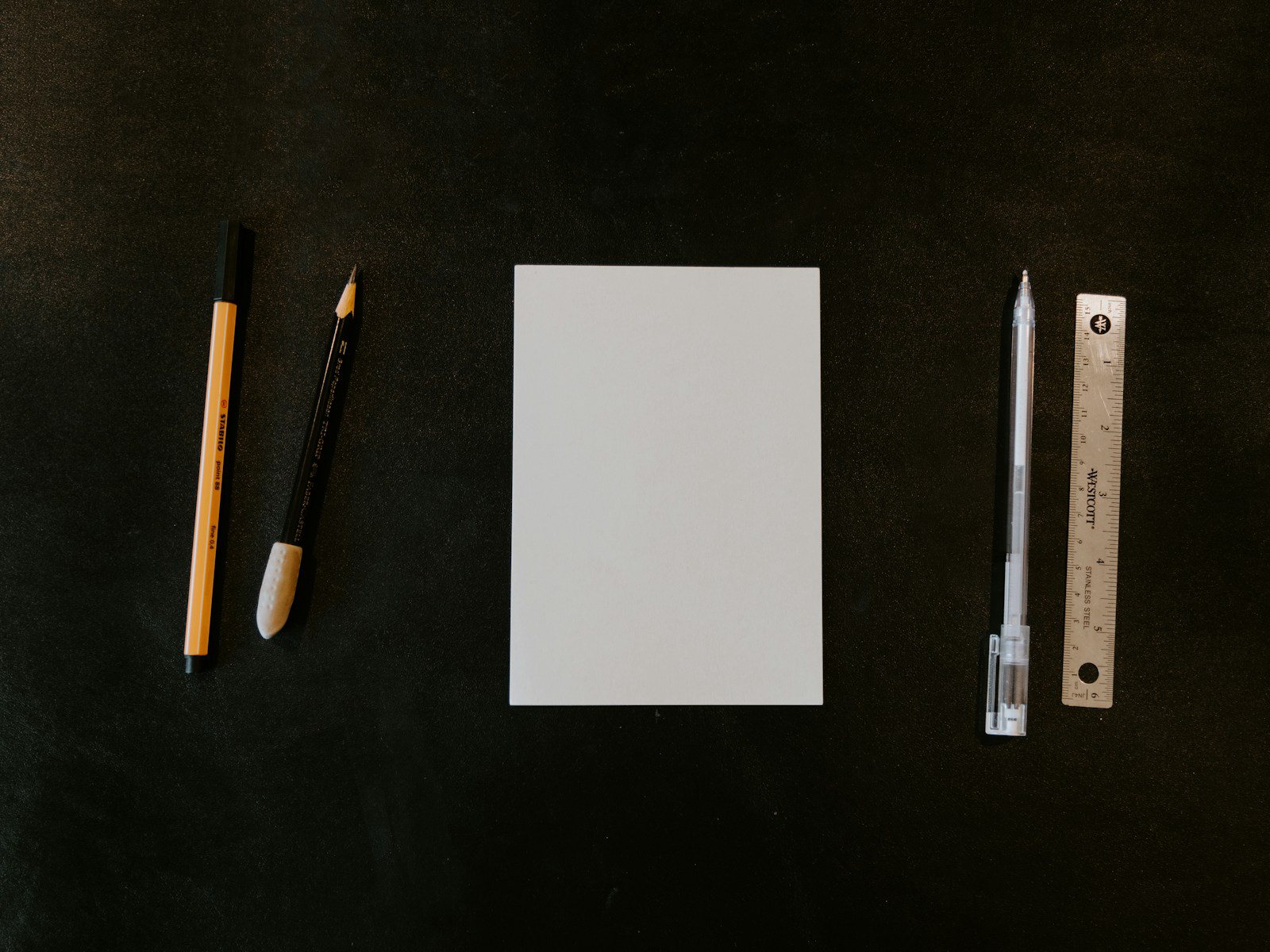 Flat lay of a steel ruler, a fan of color swatches and a blank square card on warm paper, no people